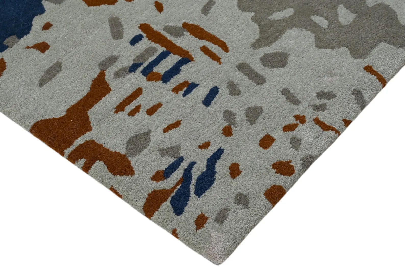Corner detail of the Abstract Pattern Area Rug with sharp distressed accents in earthy brown, blue, and light grey.