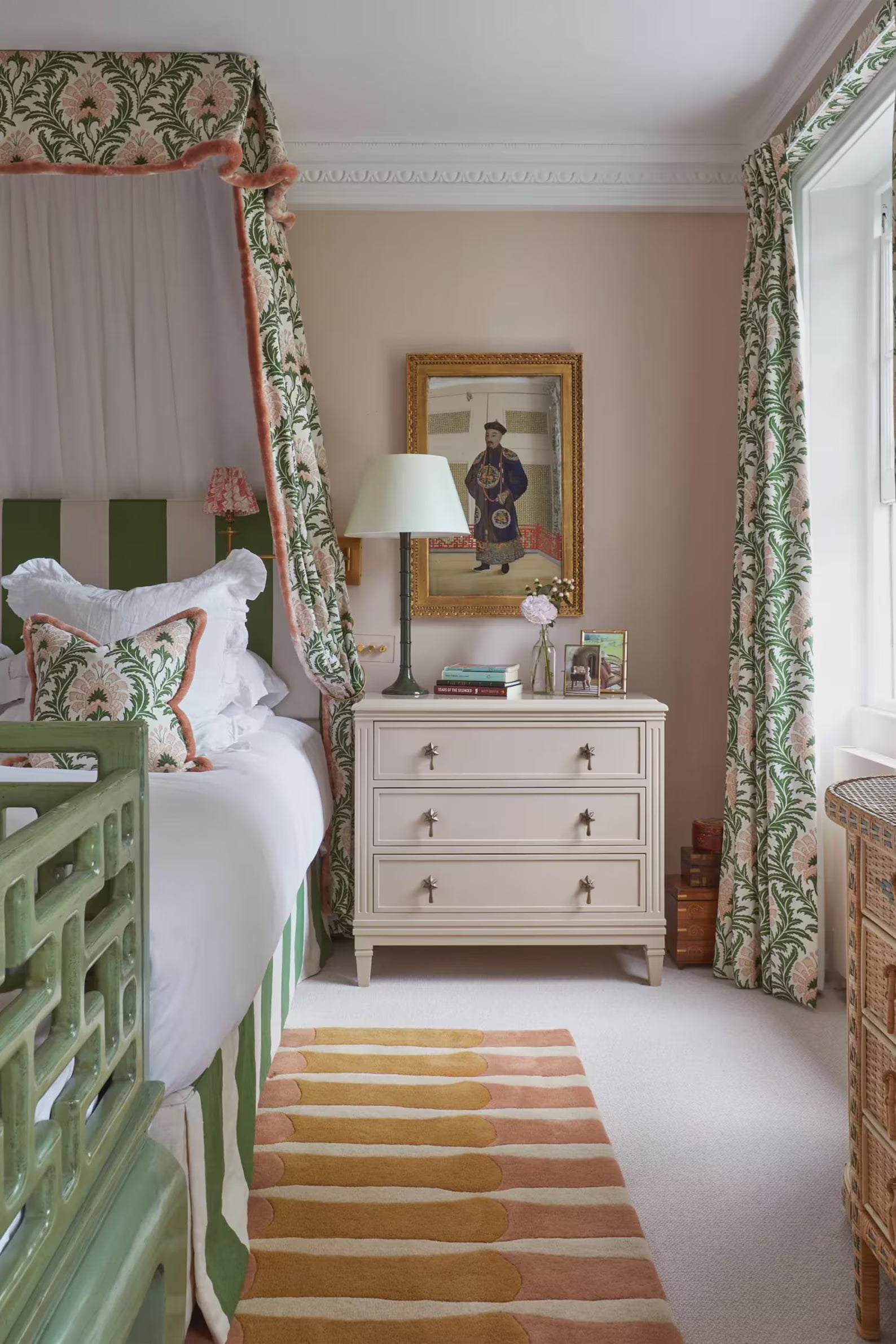 Amberline Rug placed beside a vintage bed with green floral curtains and classic decor, showcasing its soft blush and amber stripes that complement the elegant bedroom palette.