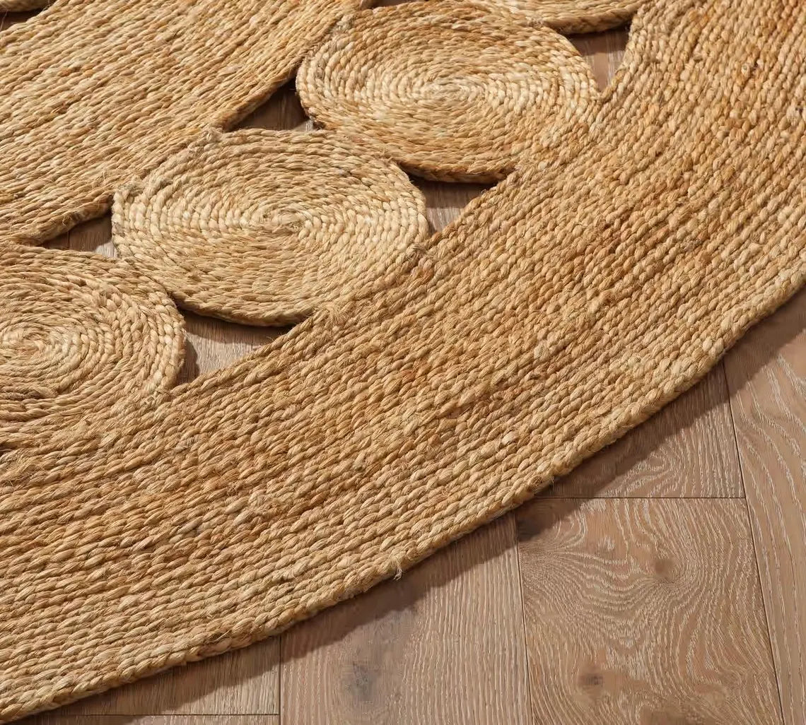 Corner view of the Bask Jute Rug showing its detailed circular weave and natural jute fibers on a wooden floor, highlighting craftsmanship and texture.