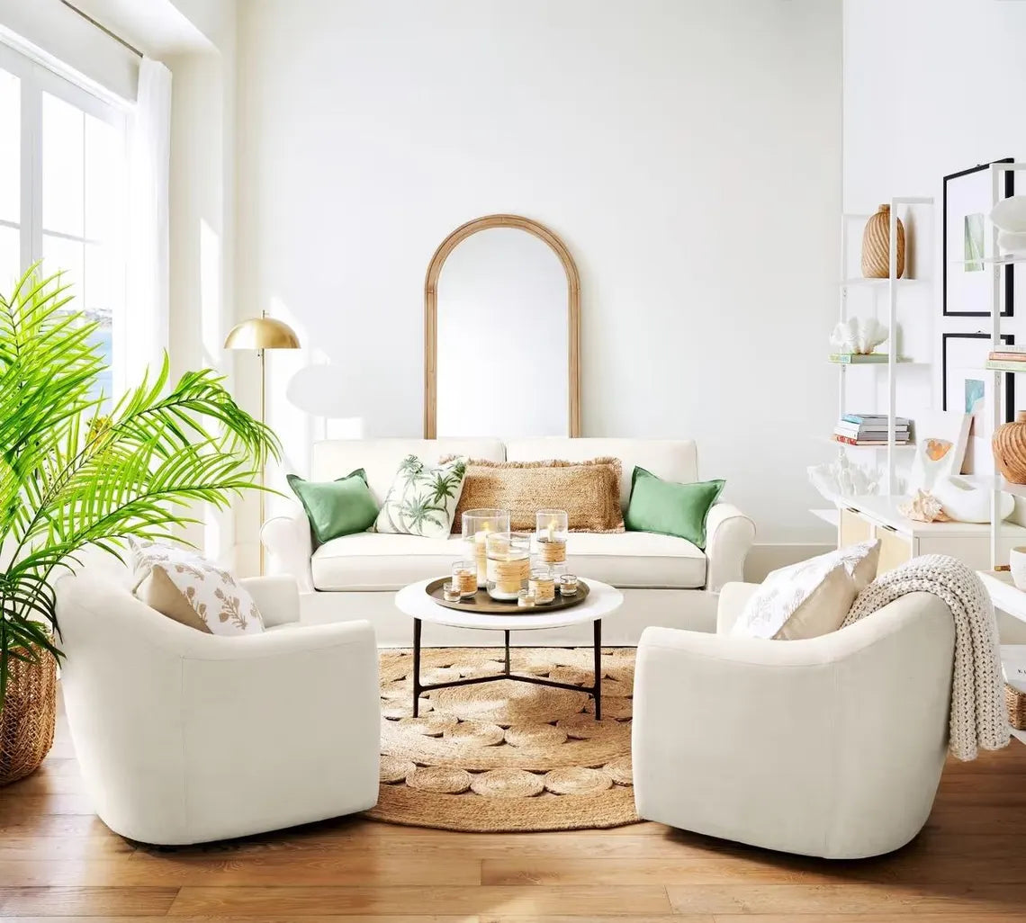 Bask Jute Rug styled in a bright living room featuring white chairs, greenery, and soft natural light showcasing the rug’s earthy tone and handwoven jute texture as the room’s focal point.