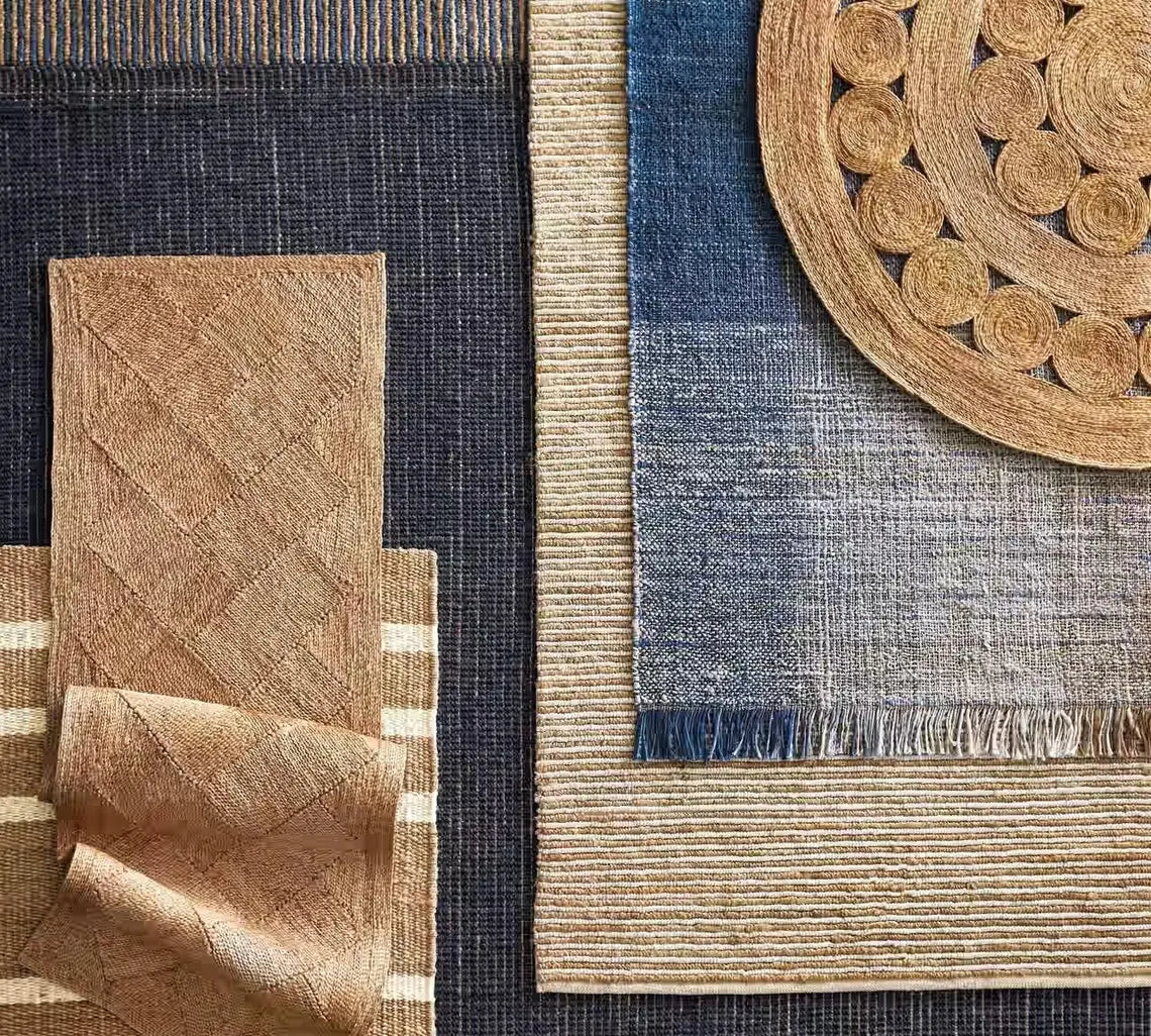 Bask Jute Rug styled flatlay showing natural jute round rug layered over blue and beige woven textiles, highlighting handcrafted details and earthy tone harmony.