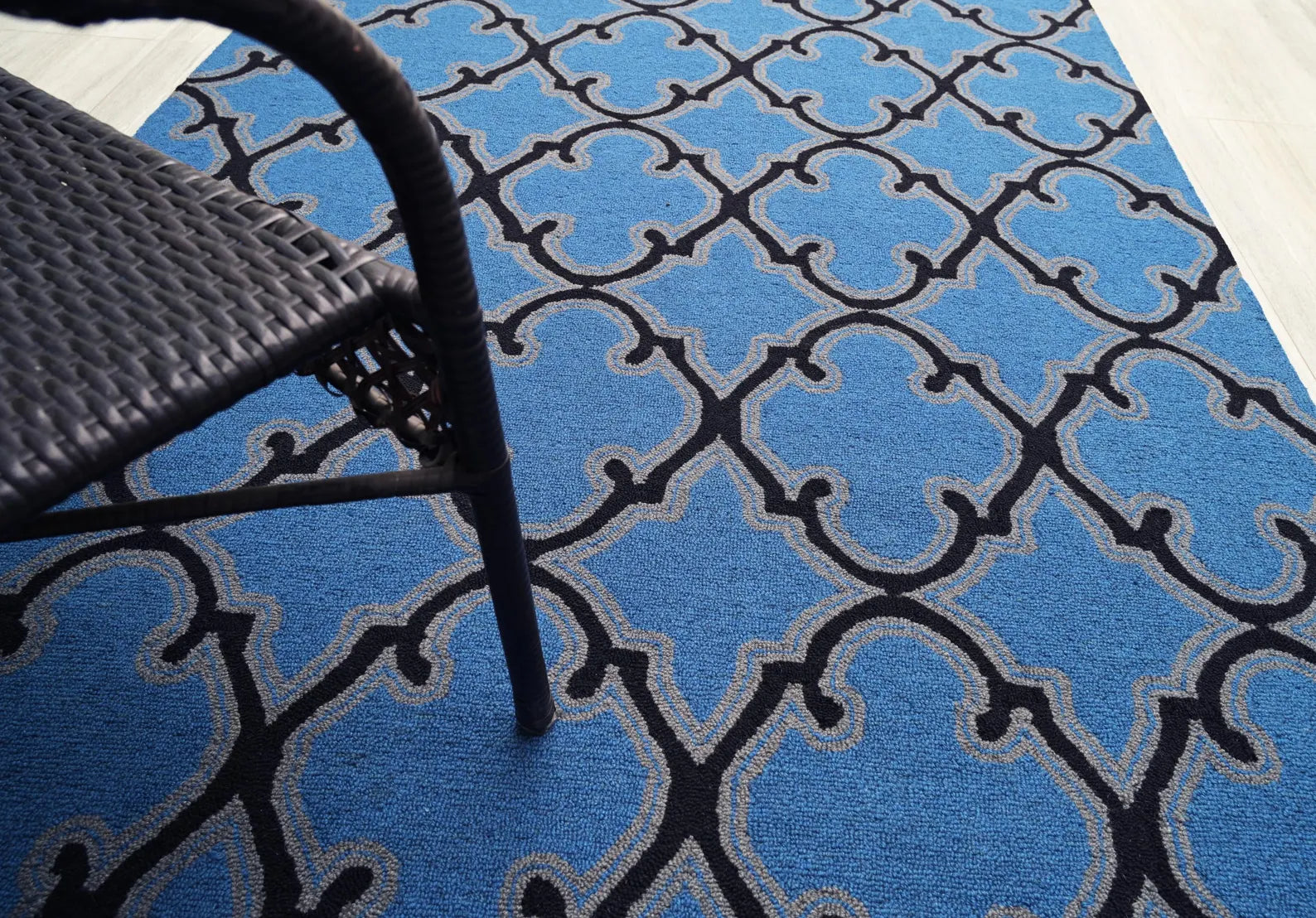 Angled view of Bluenox hand tufted rug placed on floor, showcasing its rich blue tone, black trellis lines, and soft hand-tufted surface texture.