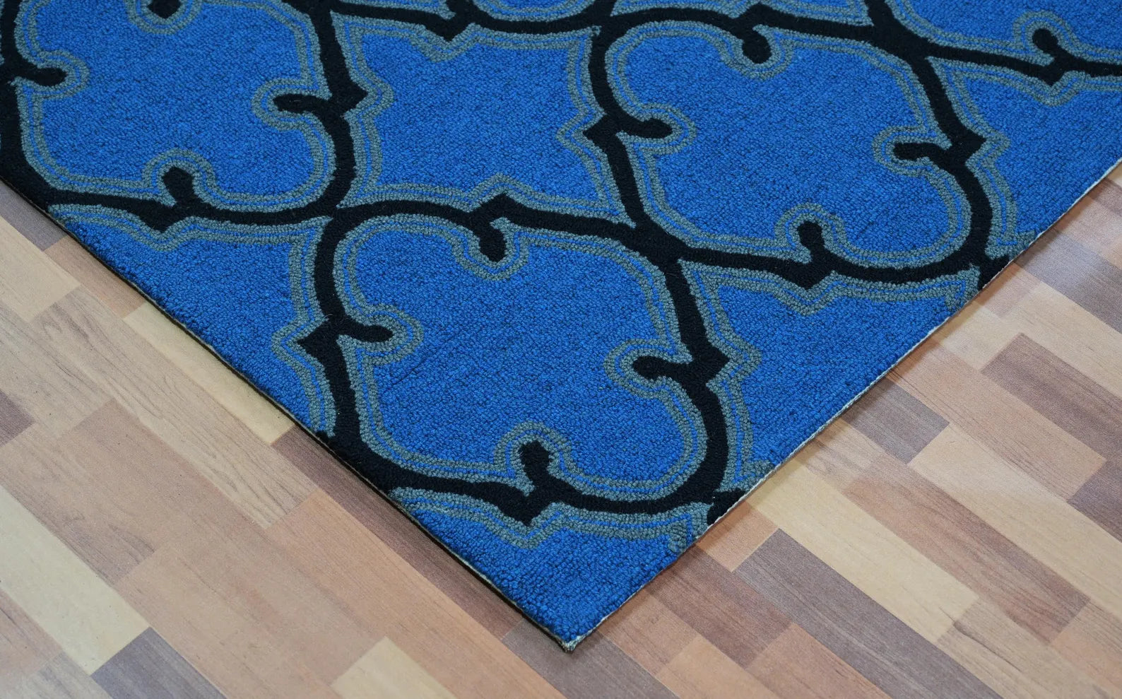 Corner close-up of Bluenox hand tufted rug showing clean hand-tufted edges, precise black trellis detailing, and rich blue wool texture.