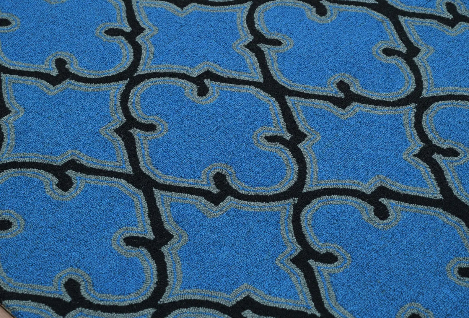 Close-up of Bluenox hand tufted rug highlighting its deep blue wool surface and intricate black geometric trellis pattern for a modern accent look.