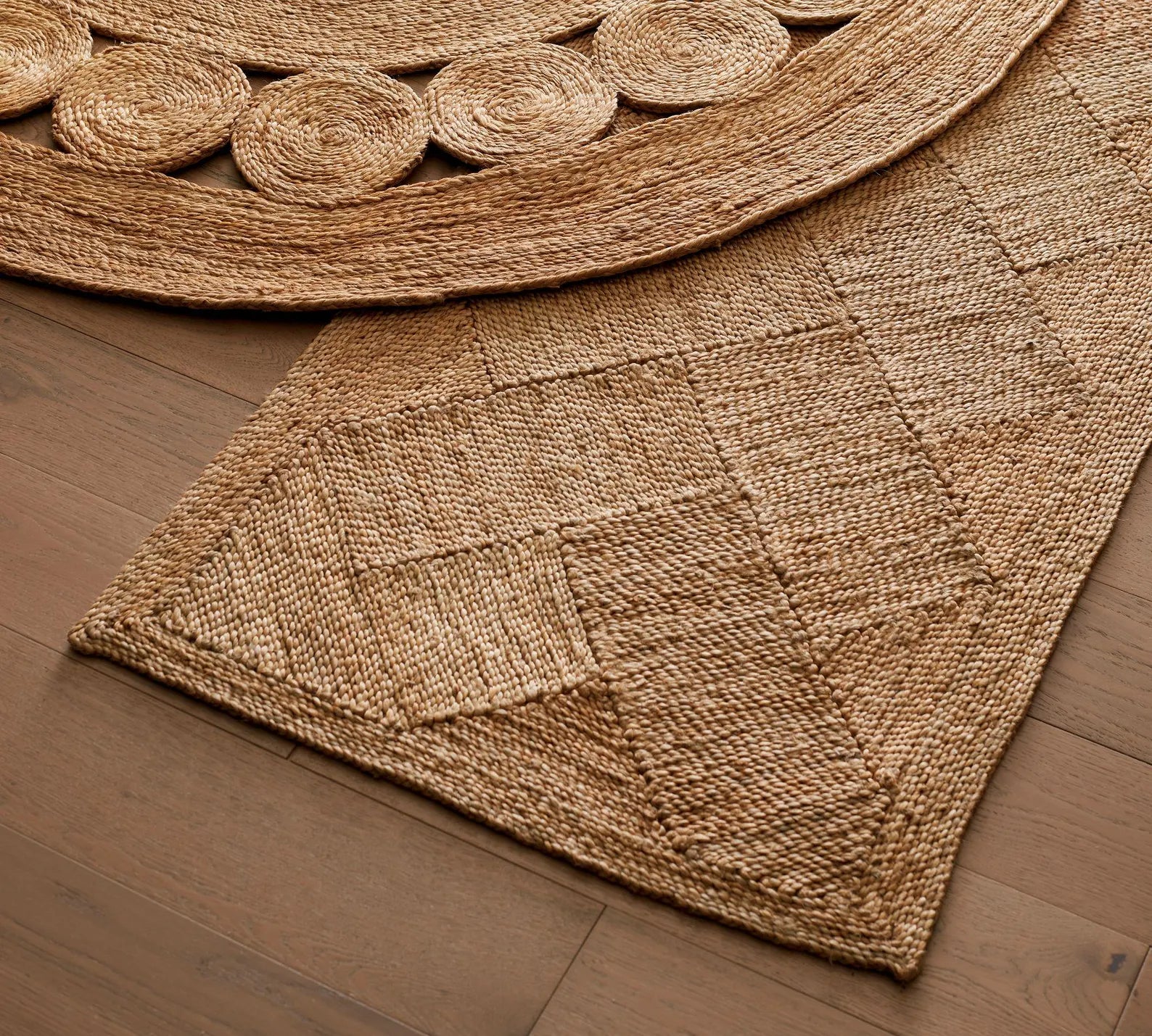 Overlapping view of Cascara Rug and round jute mat highlighting the handwoven diamond pattern and intricate braided texture on wooden flooring.