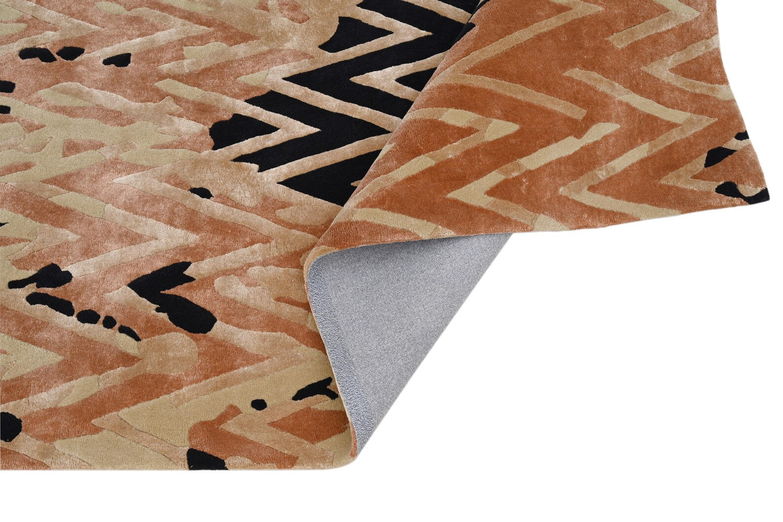Close-up of Chevron Distorted Rug showing the folded corner and soft cotton backing, highlighting the hand-tufted chevron pattern with bold black accents.