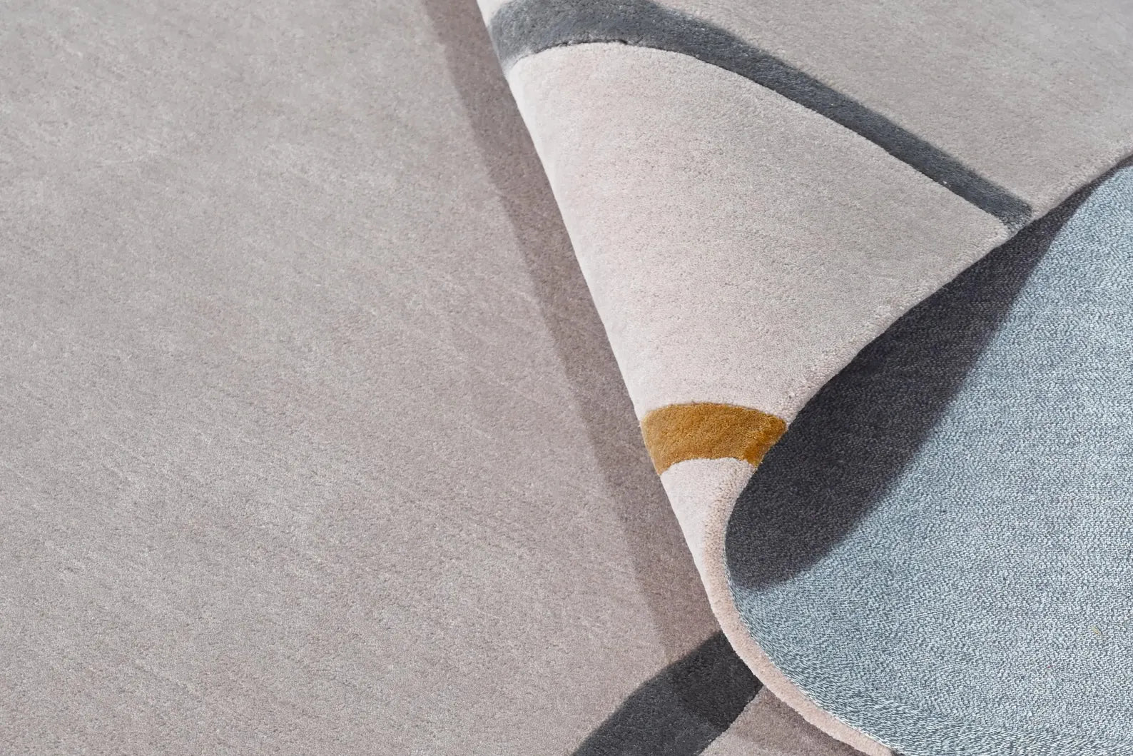 Contour Thread hand tufted rug corner fold showing layered surface, fine hand tufted detailing, and abstract linear design in beige, grey, and mustard tones
