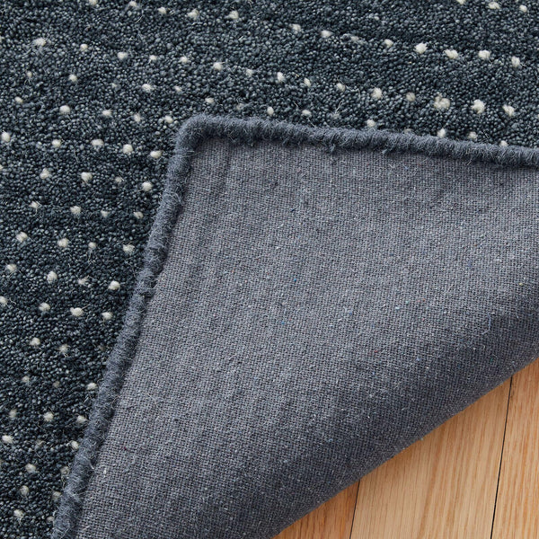 Folded corner of the Driftstone Rug showing the durable cotton backing and detailed surface texture.