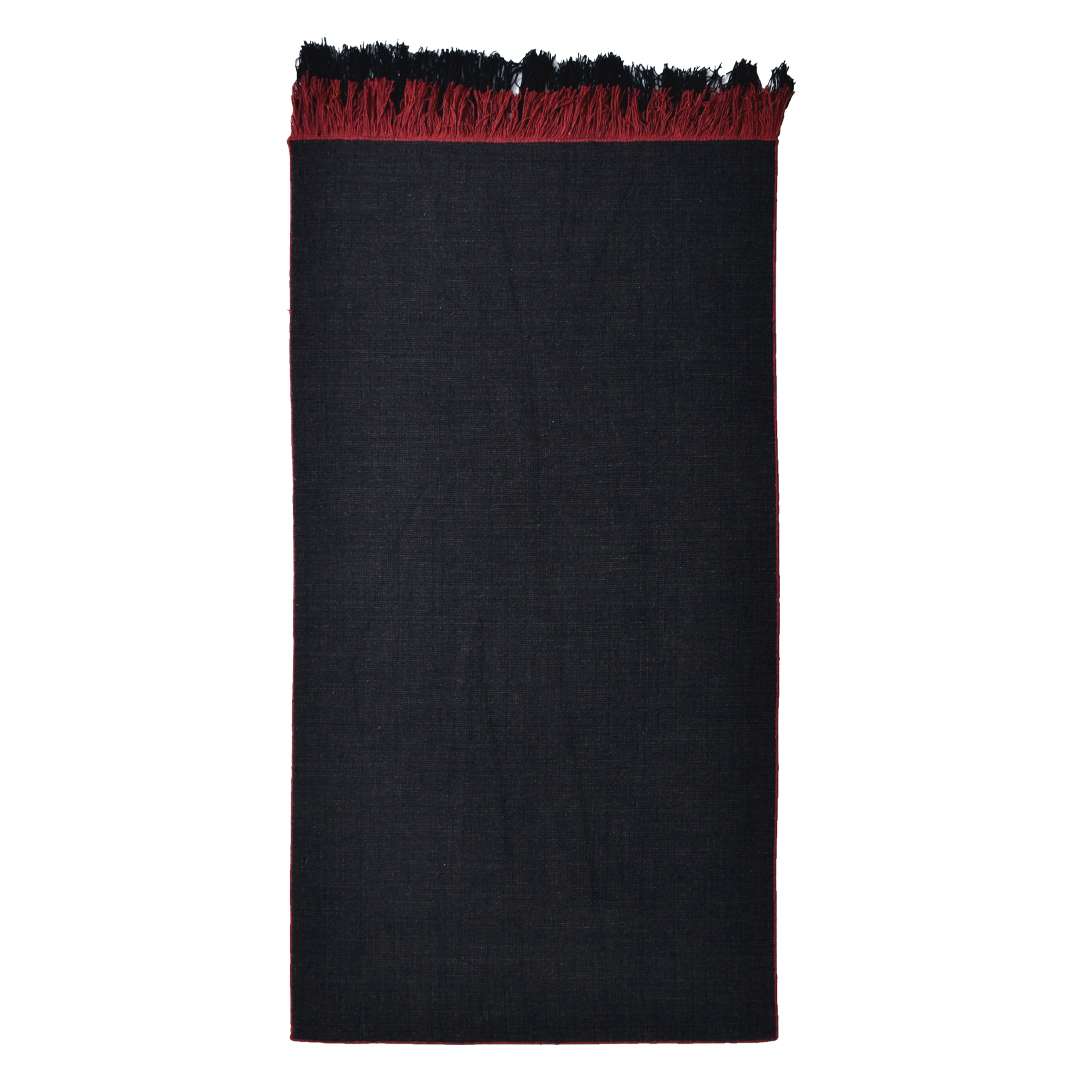 Flat lay view of Auskin Luxury Black Rug showing uniform black wool surface with red borders