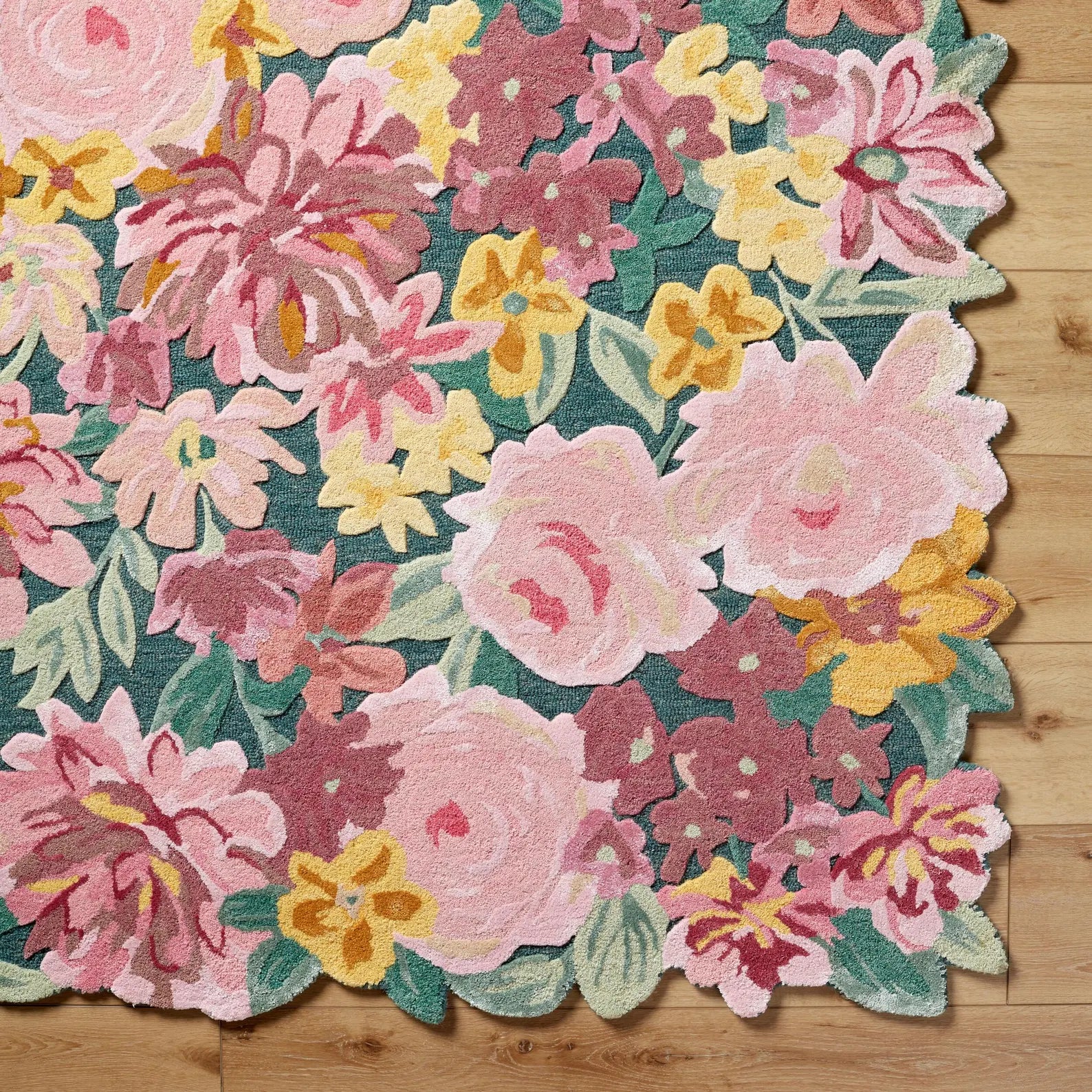 Floral Fantasy Wool Rug corner  showing sculpted floral edges and hand tufted wool texture with vibrant pink, yellow, and green blossoms on a natural base