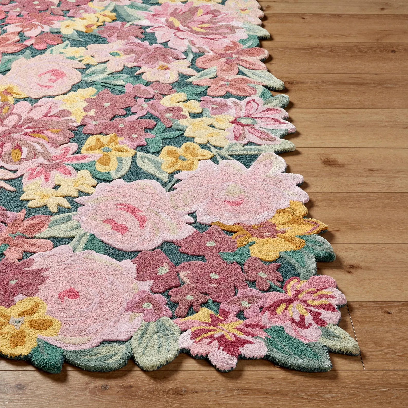 Floral Fantasy Wool Rug corner view showing sculpted floral edges and hand tufted wool texture with vibrant pink, yellow, and green blossoms on a natural base