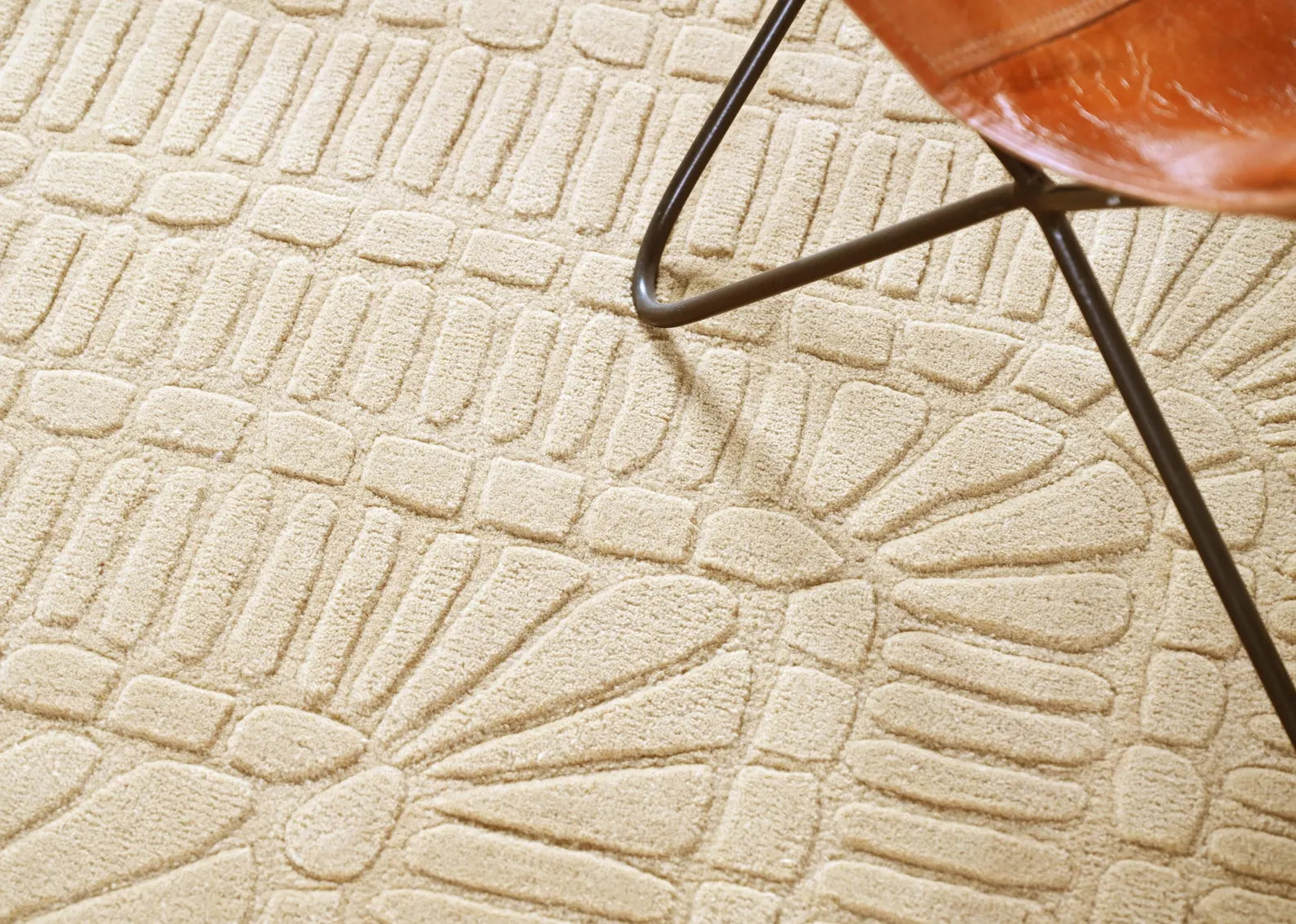 Grid Wool Rug styled under a chair, showcasing geometric carved textures.