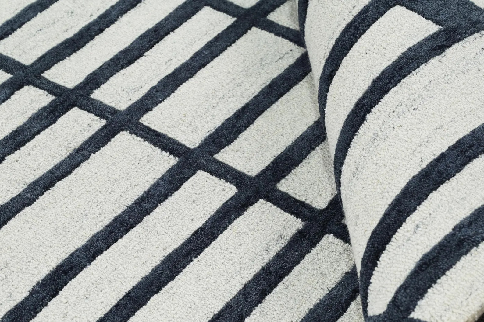Detailed view of Gridlock Rug edge showing craftsmanship, stitching quality, and defined geometric alignment.