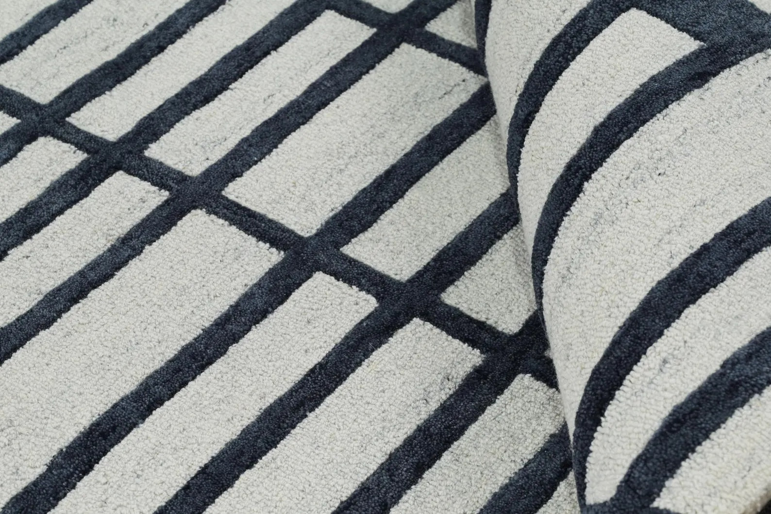 Corner view of Gridlock hand tufted rug showing crisp black grid lines on an ivory base with soft hand-tufted wool texture.