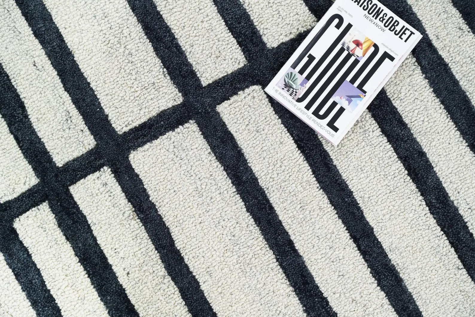 Close-up of Gridlock hand tufted rug showing raised black lines and soft wool pile on a white background.