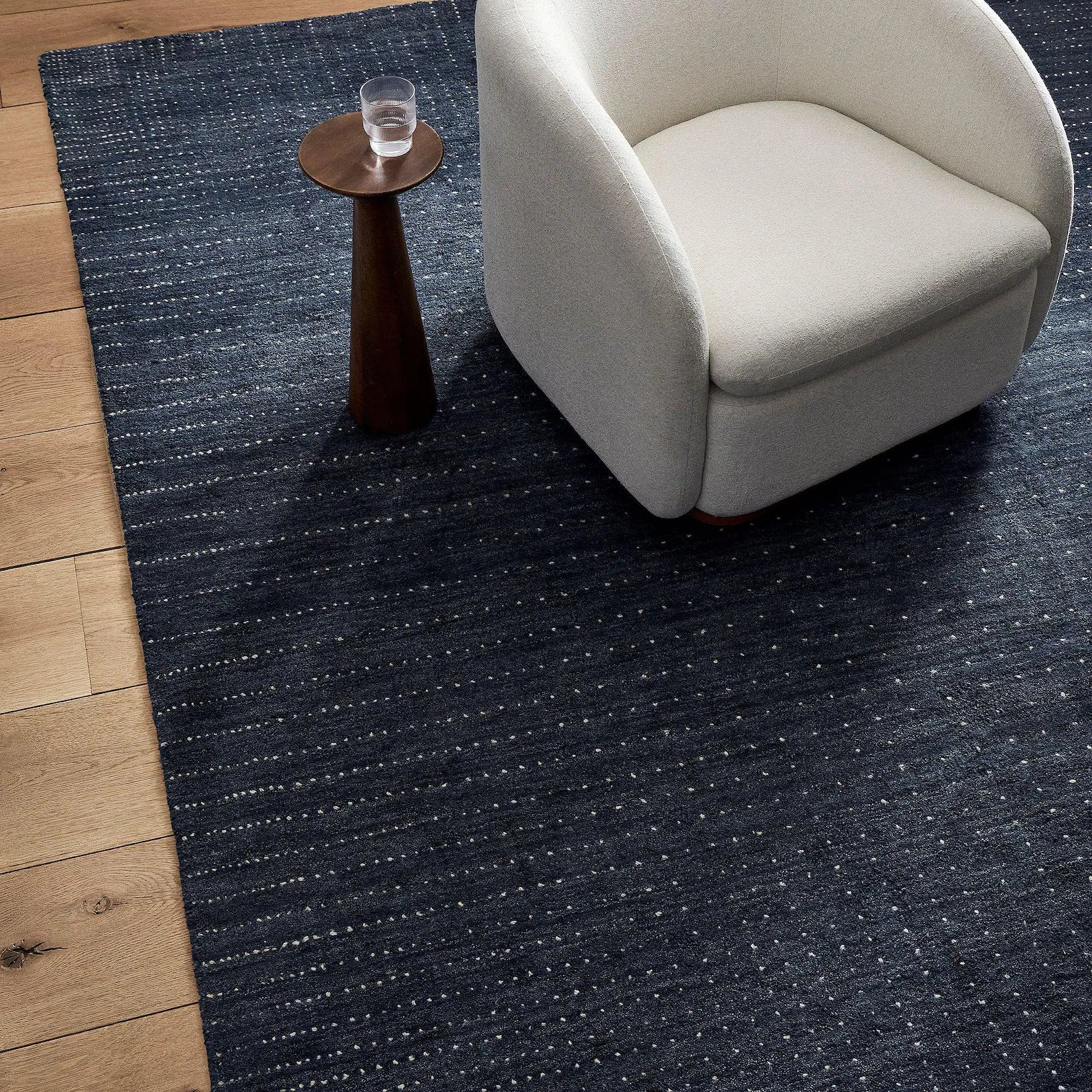 Indigo dot texture wool rug styled with chair and table on wooden floor – handmade by Decordec