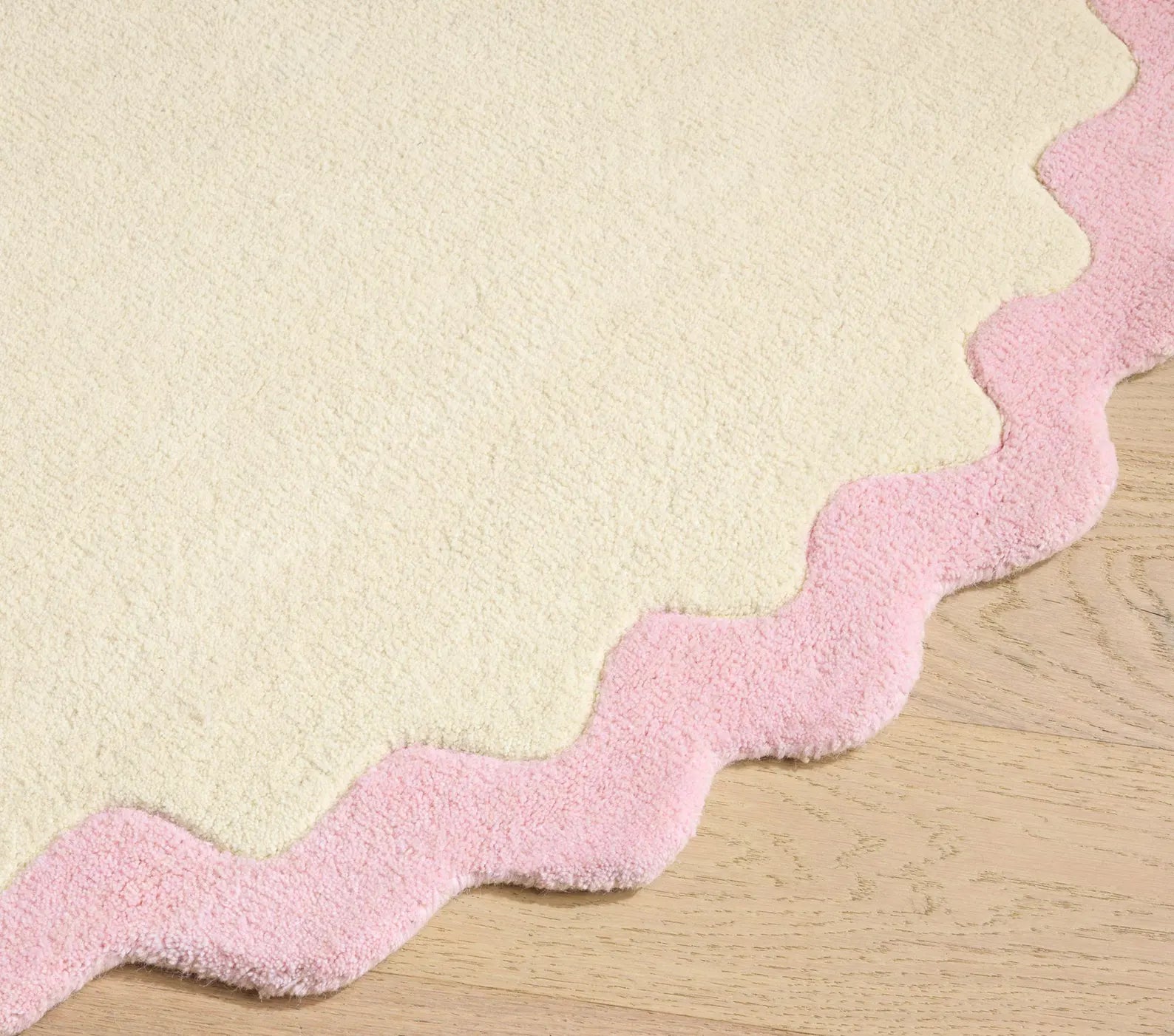 Lullaby Rug round version showing soft wavy pink edge detailing on an ivory backdrop