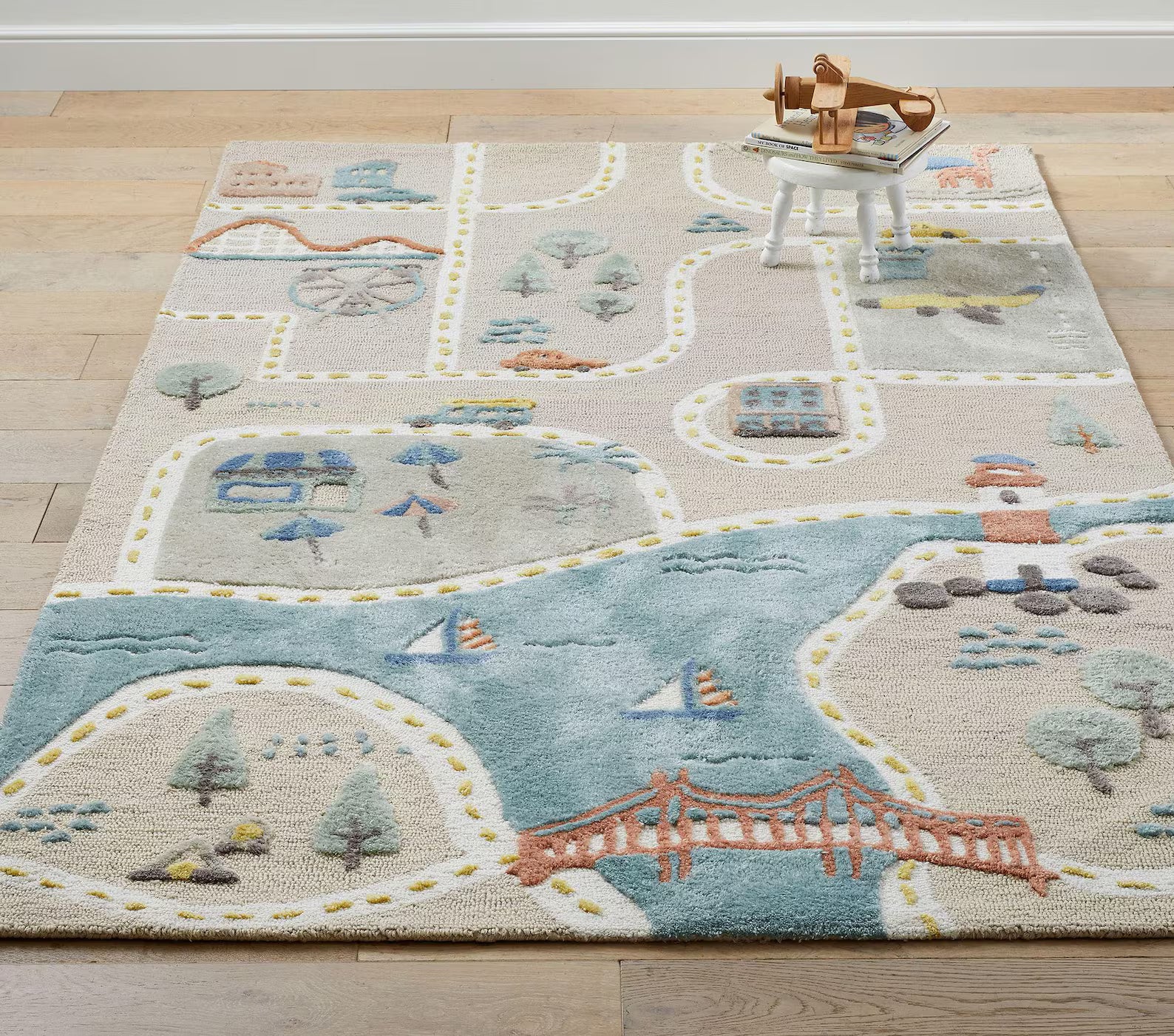 Full top-angle view of MiniCity Rug featuring pastel city map details with roads, bridges, parks, and rivers on a wooden floor.