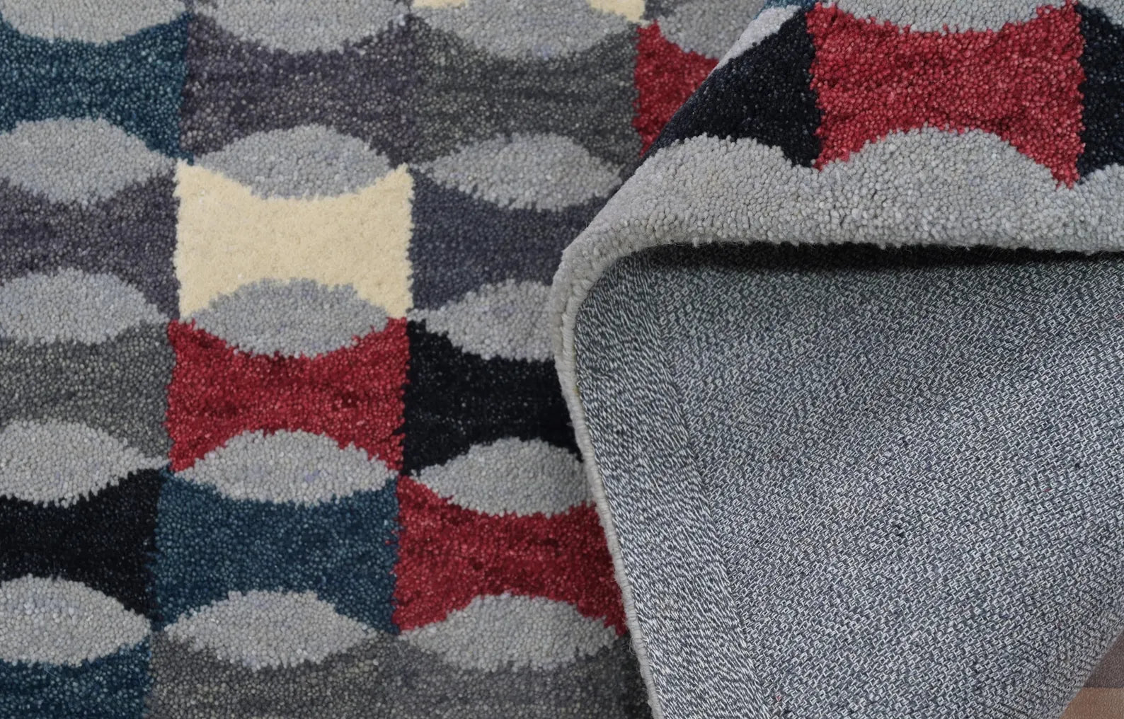Close-up view of Monotone Matrix Rug showcasing its textured hand-tufted geometric design in shades of grey, white, and red.