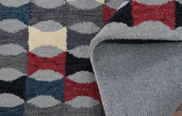 Close-up view of Monotone Matrix Rug showcasing its textured hand-tufted geometric design in shades of grey, white, and red.