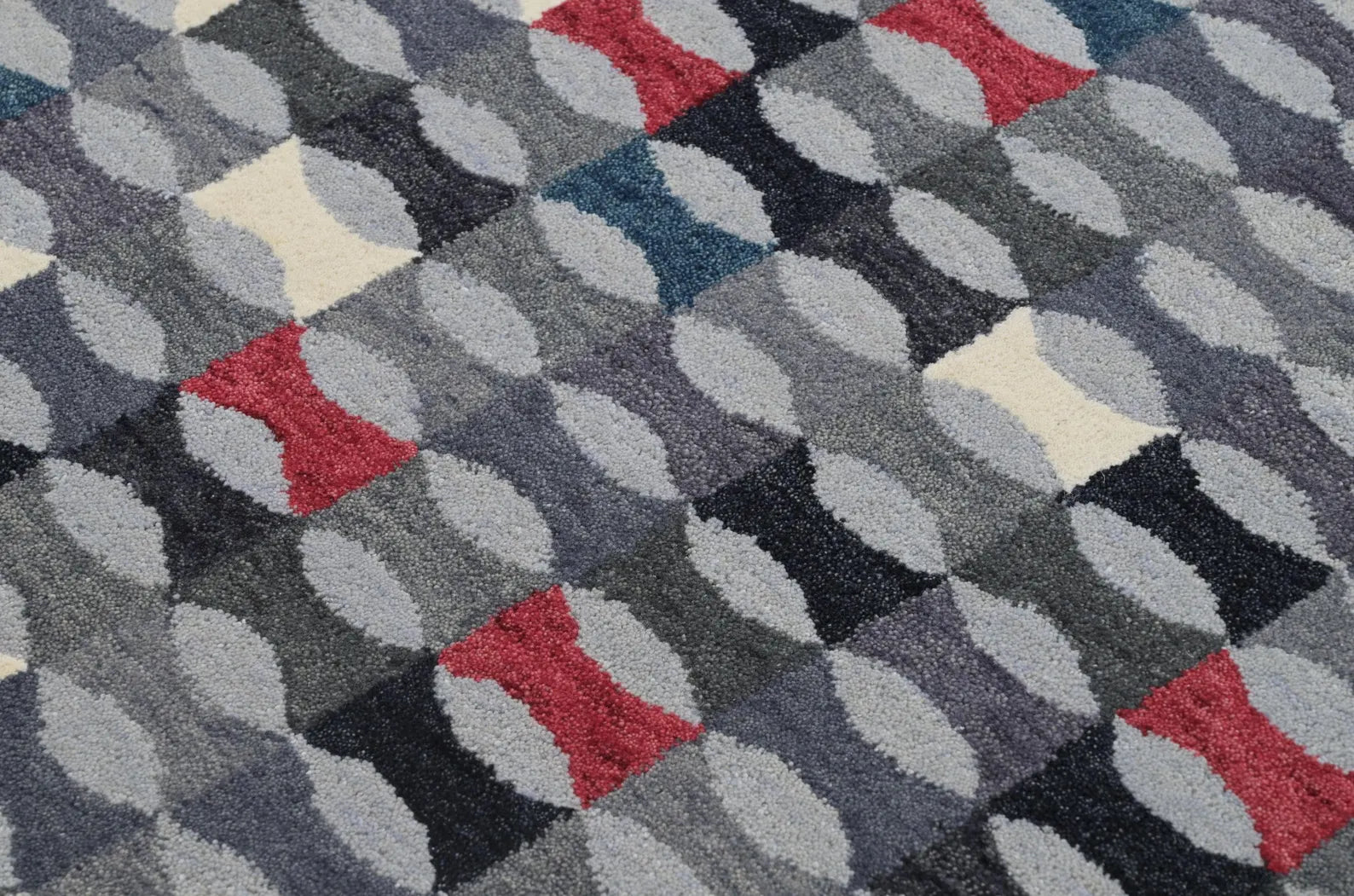 Close-up texture view of Monotone Matrix Rug highlighting its hand-tufted geometric pattern in grey, red, white, and charcoal tones.