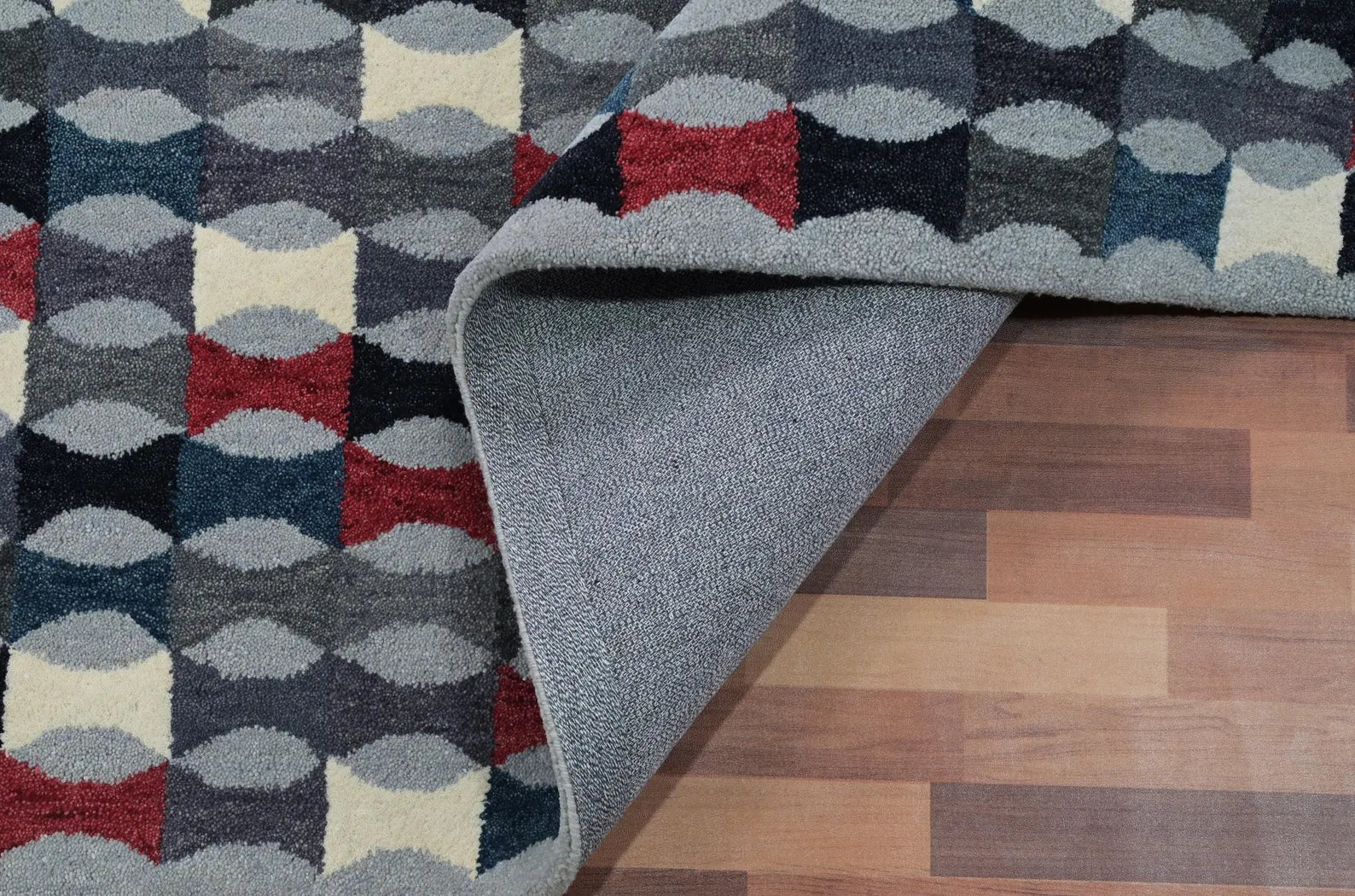 Monotone Matrix hand tufted rug edge showing neat binding and precise craftsmanship in soft grey tones with red highlights.