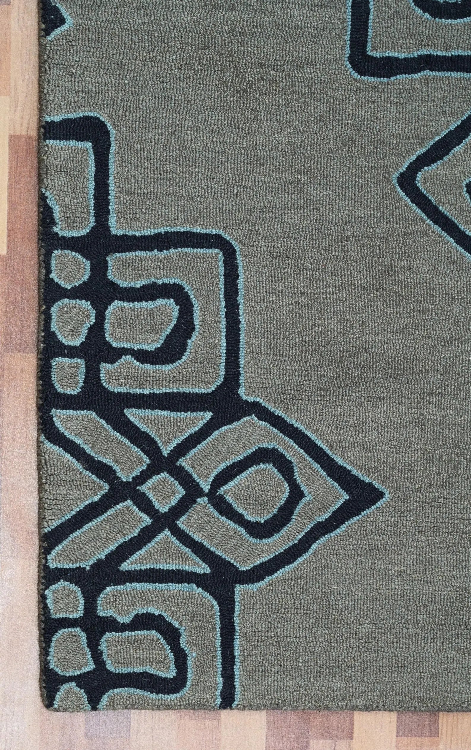 Close-up of the Navier rug’s refined edge detailing and navy geometric pattern on a textured grey base.