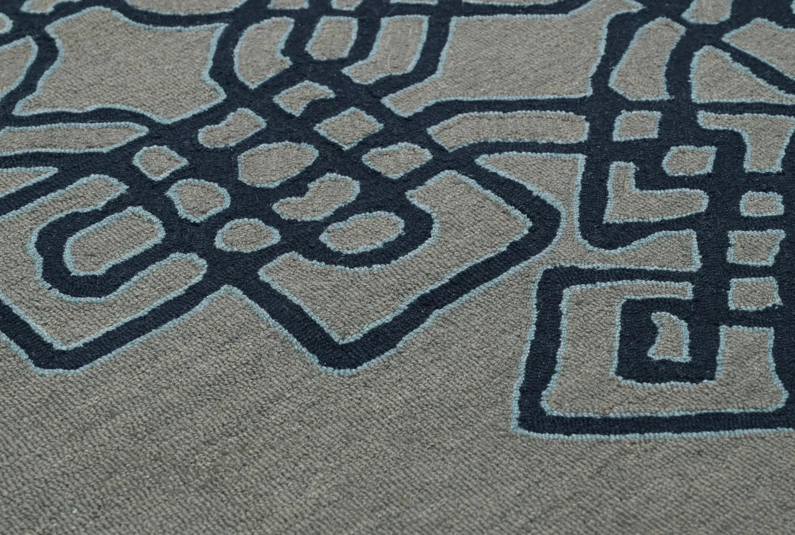 Detailed close-up of Navier hand tufted rug showing raised navy blue geometric pattern on a soft grey base.