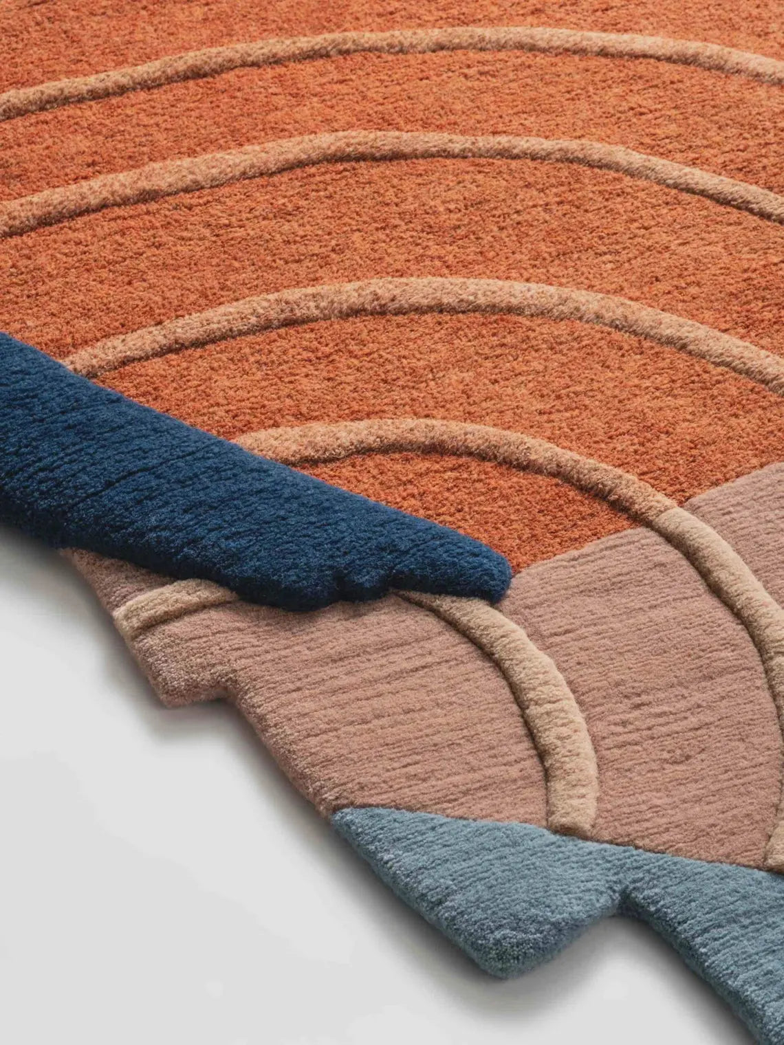 Close-up of Petra Rug showing terracotta and blue carved textures.