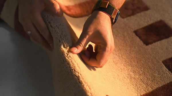 Hand touching the Pixelated Rug surface, showcasing its hand tufted texture