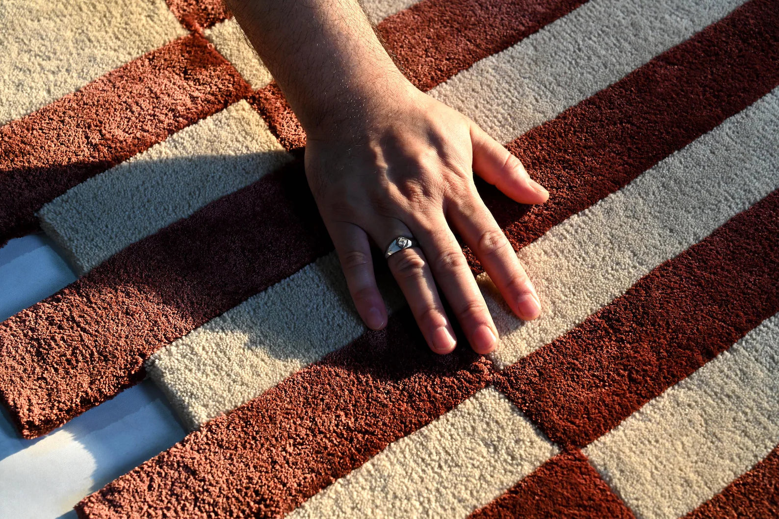 Hand touching the Pixelated Rug surface, showcasing its hand tufted texture.