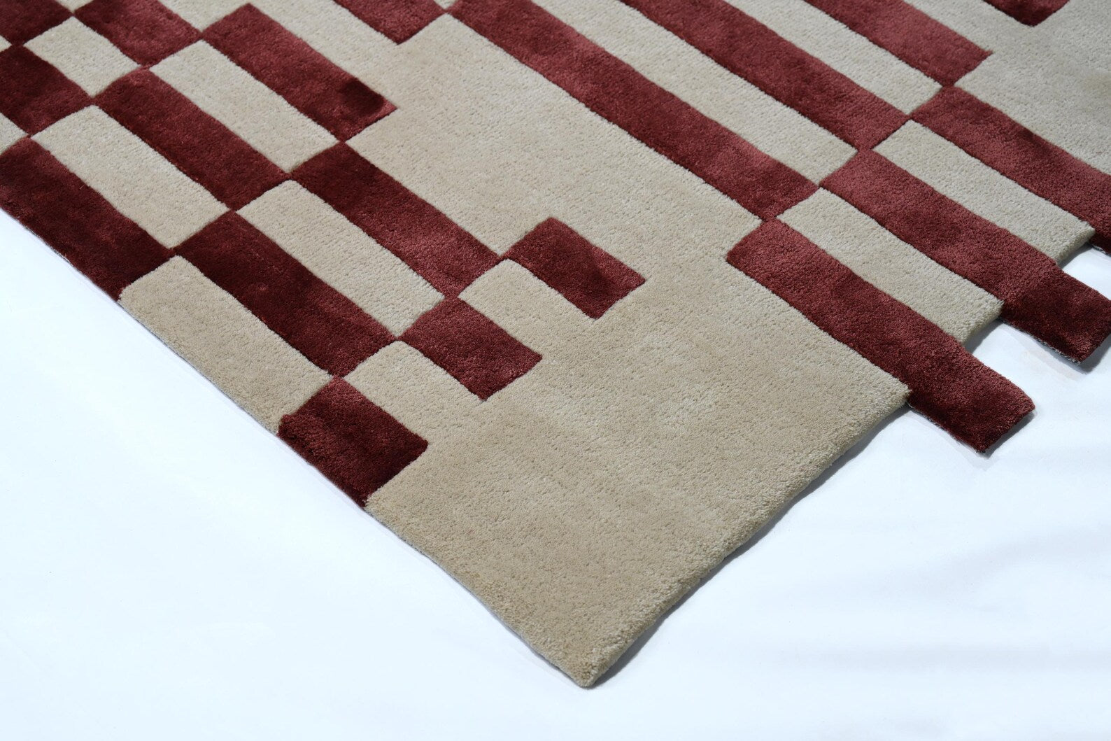 Corner shot  of Pixelated Rug pattern with geometric burgundy lines.