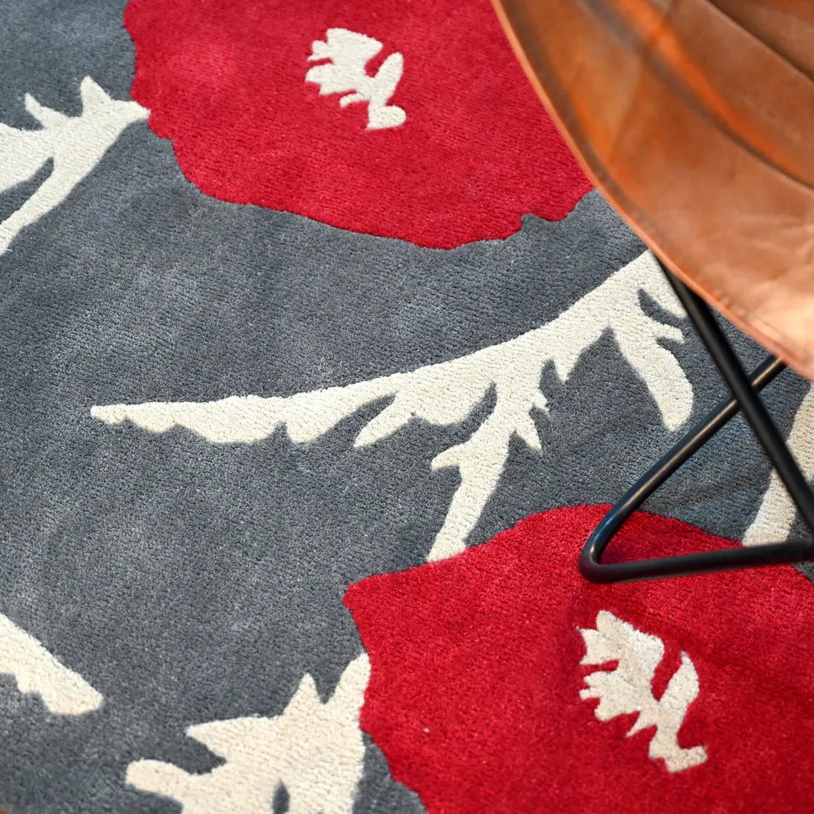 Detailed view of the Poppy Bloom Rug showing bold red floral pattern on a gray base.
