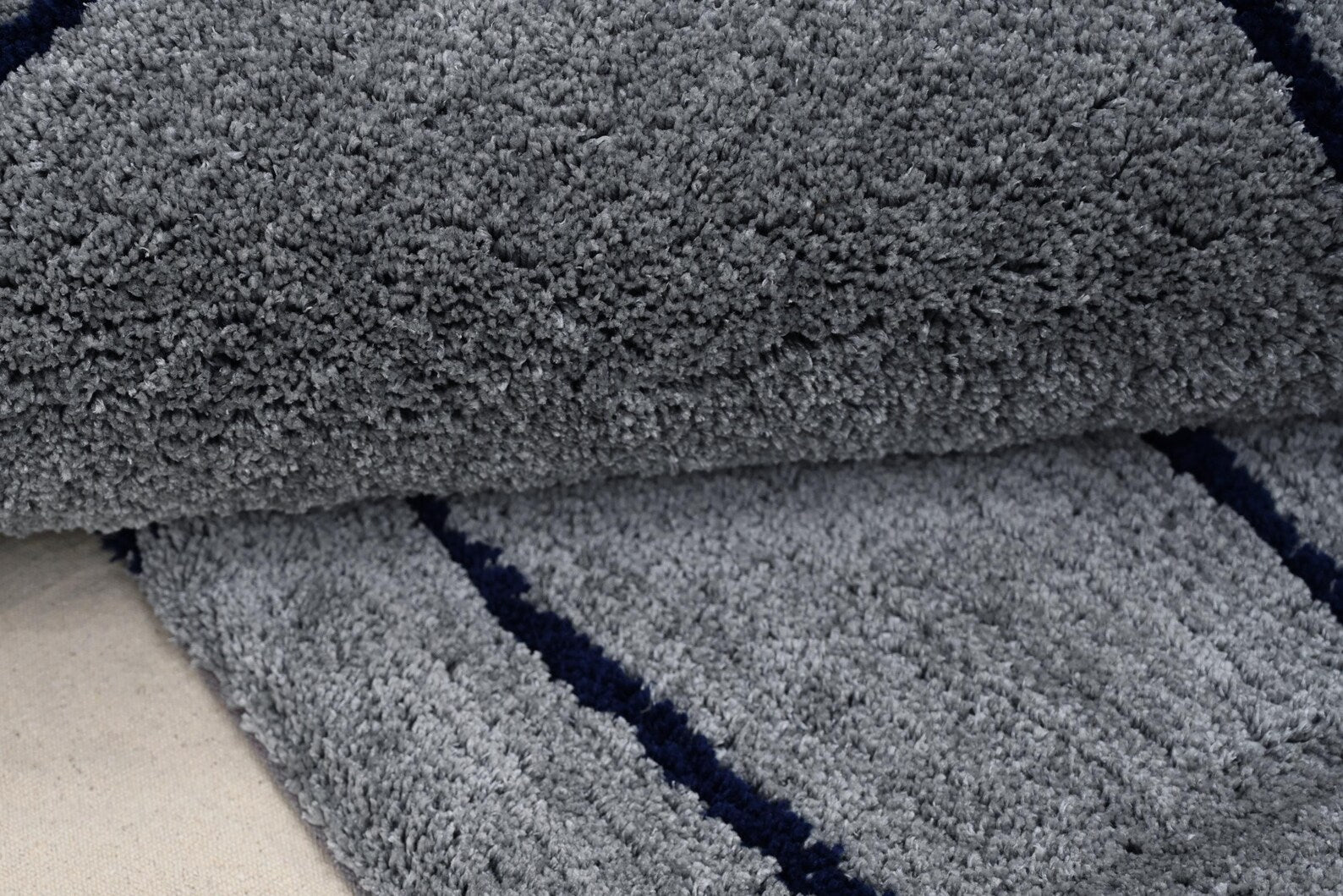 Rolled texture view of Abstract Line Art Grey Rug showing thick grey pile with dark abstract lines and soft handcrafted surface