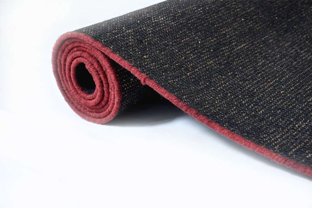 Rolled view of Auskin Luxury Black Rug showing rug thickness and smooth finishing in black and red accent