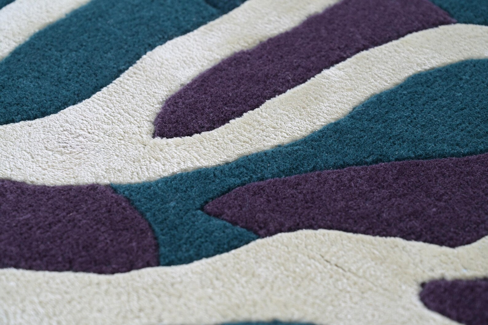 Seaform Hand tufted Rug texture closeup highlighting high low tufting and smooth pile finish in teal, ivory, and plum tones under natural daylight
