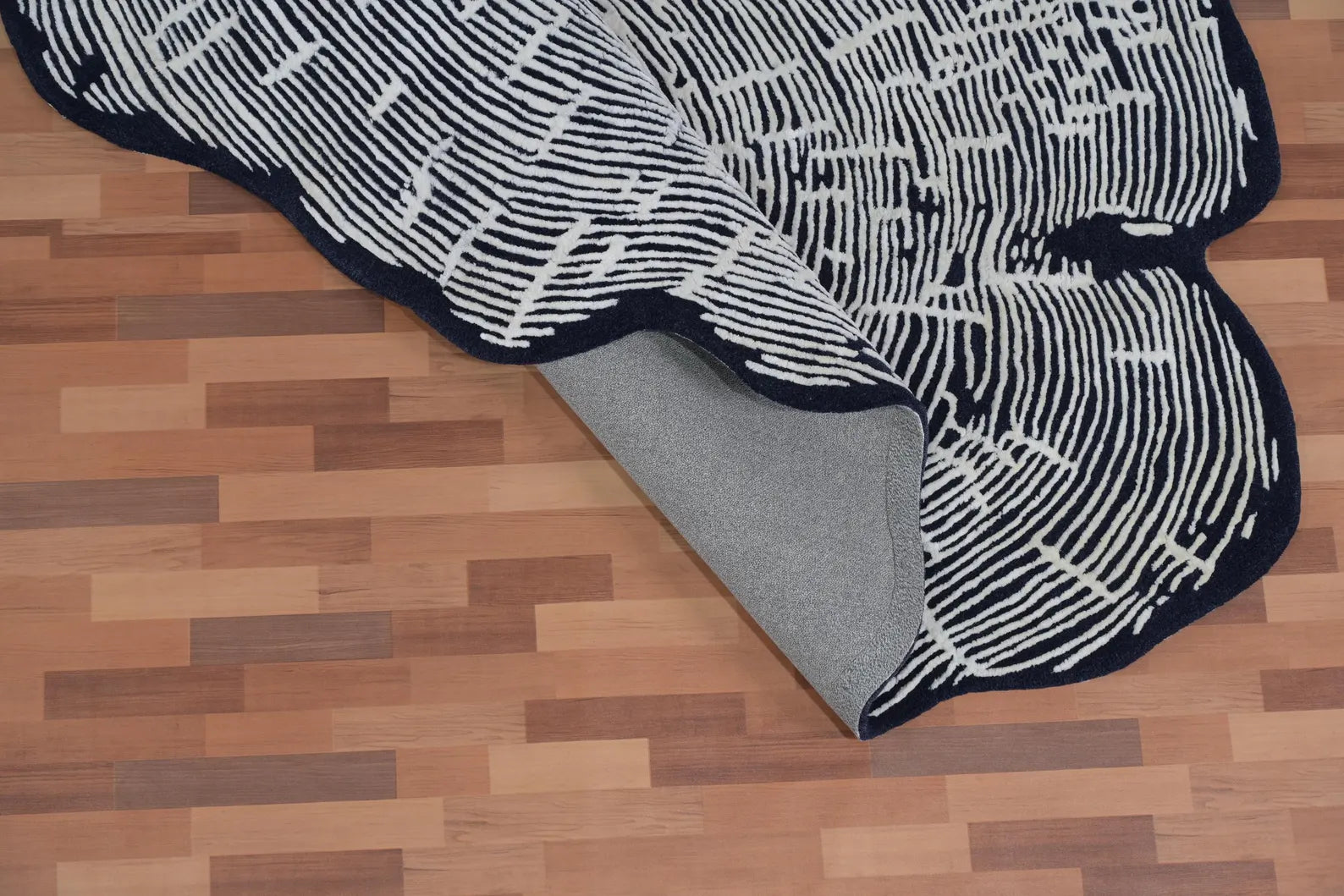 Sequoia Rug folded at the corner showing its durable wool backing, soft hand-tufted surface, and intricate white line detailing on a dark base.