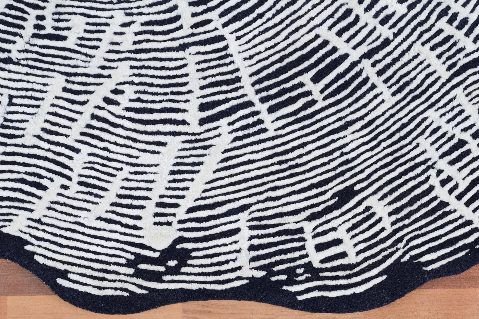 : Close-up texture view of Sequoia Rug showing detailed hand-tufted white linear pattern on a dark charcoal wool base with soft high-low texture.