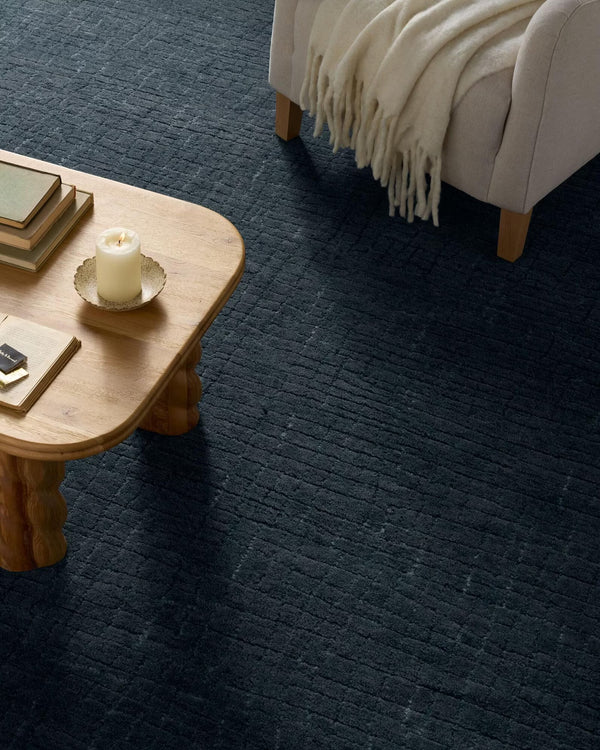 Serenity Textured Rug placed under a wooden coffee table beside a beige sofa, styled with a cozy throw for a calm and modern aesthetic.