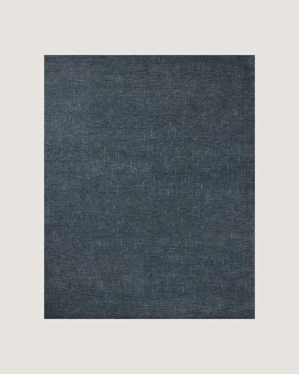 : Overhead flatlay of the Serenity Textured Rug showing its fine woven detailing and deep blue texture on a wooden floor.