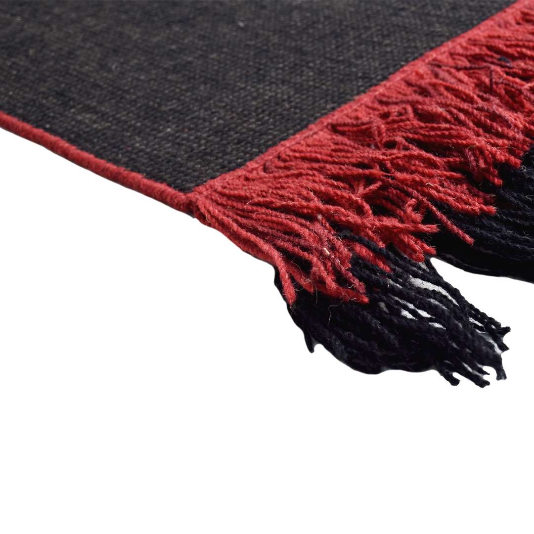 Close-up of Auskin Luxury Black Rug highlighting red fringed tassels and tight woven detailing