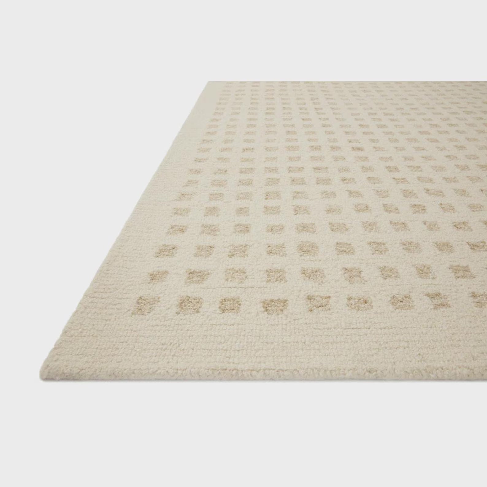 Close-up of the Tessel hand tufted rug showing its soft beige tone, structured weave, and gentle raised grid pattern.
