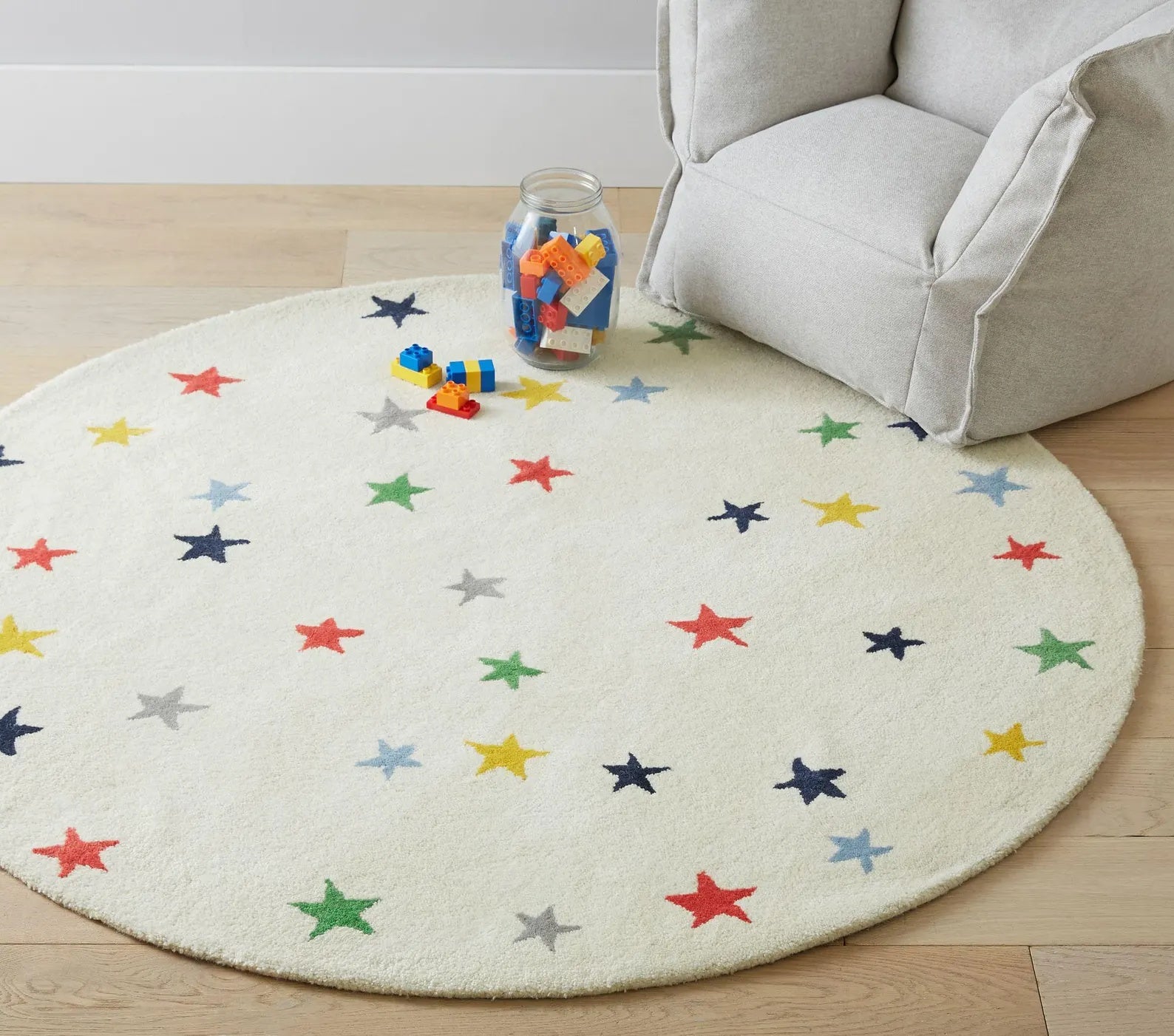 Close-up of Twinkle Rug showing colorful stars on a soft ivory background with hand-tufted wool texture.
