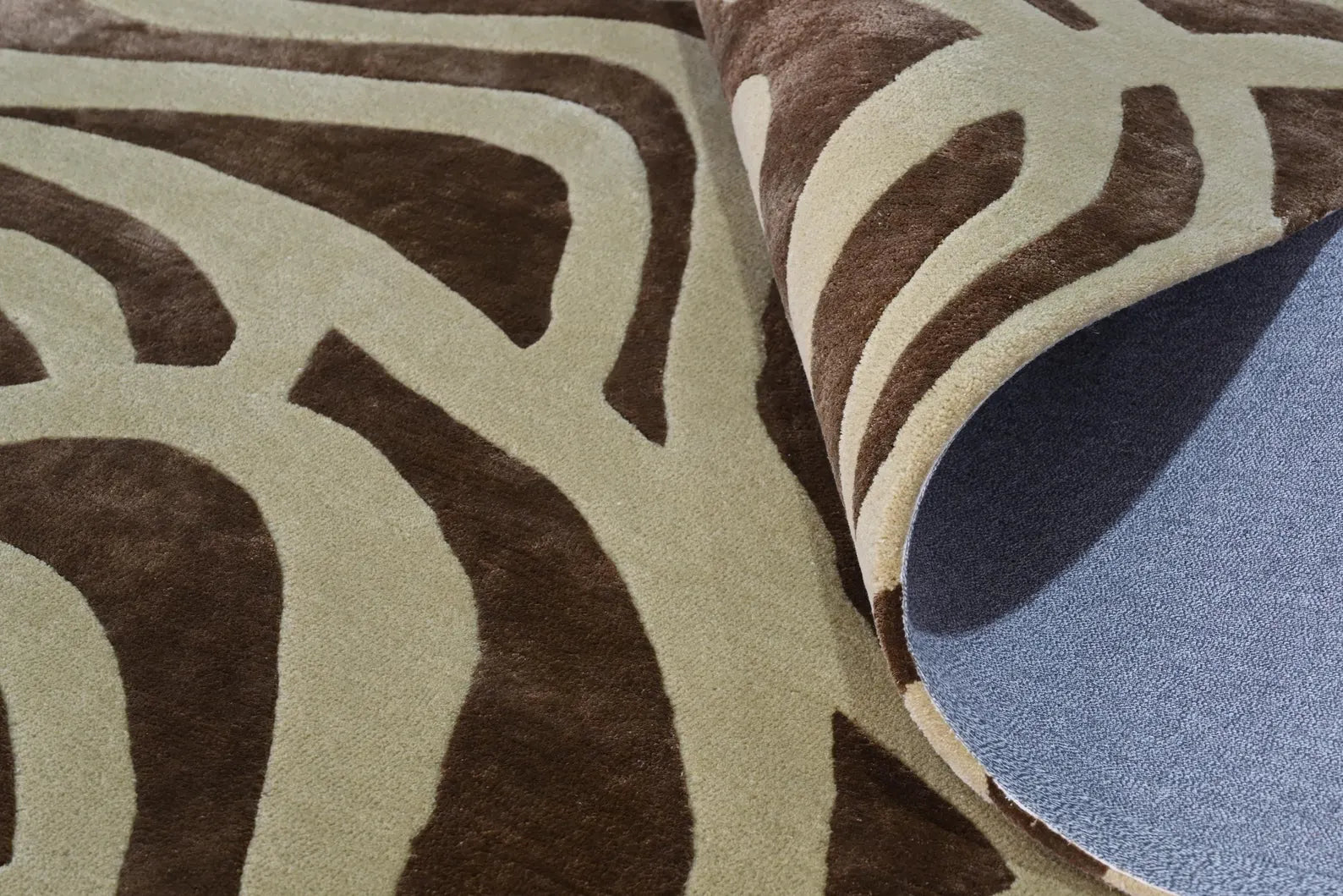 Verona hand tufted rug folded to display soft cotton backing with organic pattern detailing and precise edge finishing.