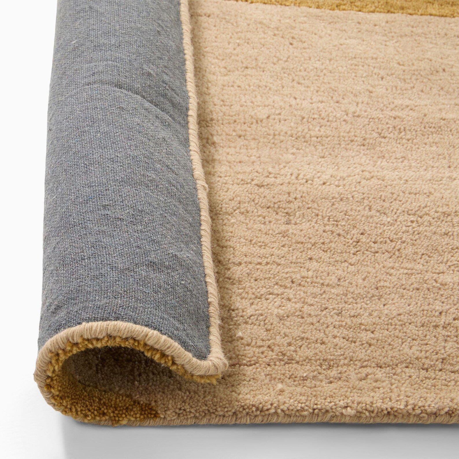 arcmist hand tufted wool rug close up of rolled corner in grey and beige with soft textured surface