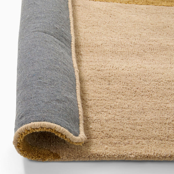 arcmist hand tufted wool rug close up of rolled corner in grey and beige with soft textured surface