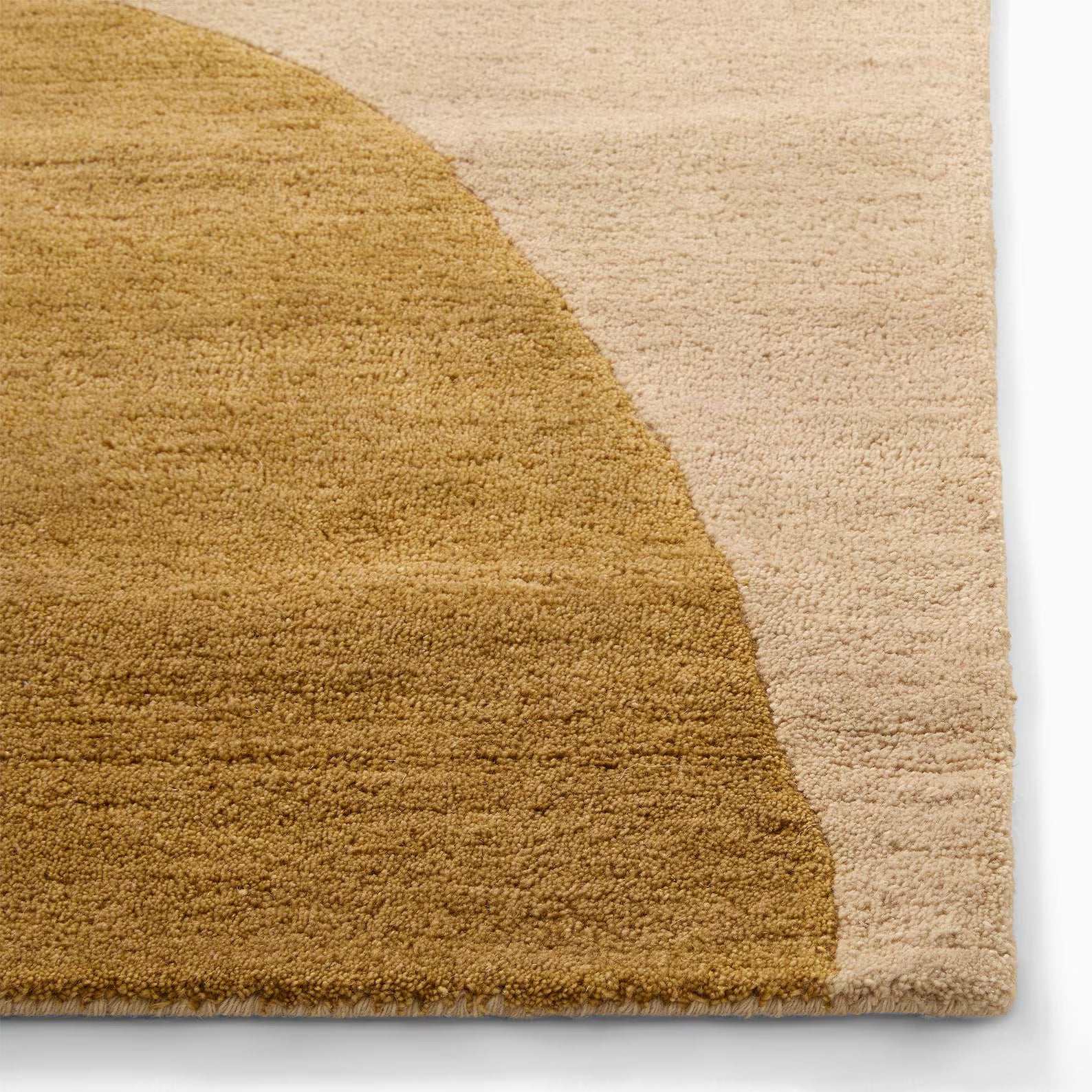 arcmist hand tufted wool rug close up showing warm ocher arc meeting beige base