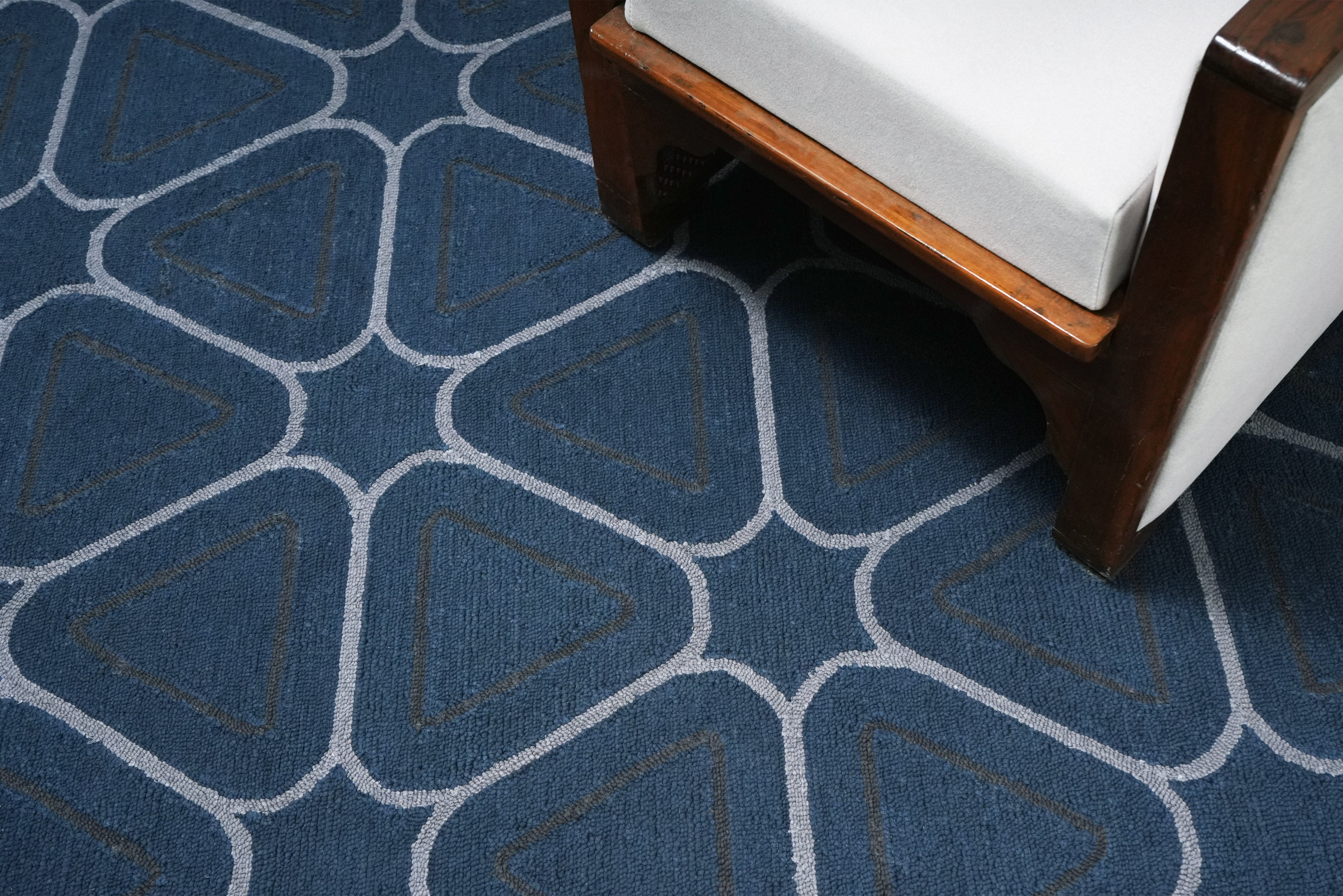 Arvelo hand tufted blue geometric rug placed in modern interior setting under furniture.