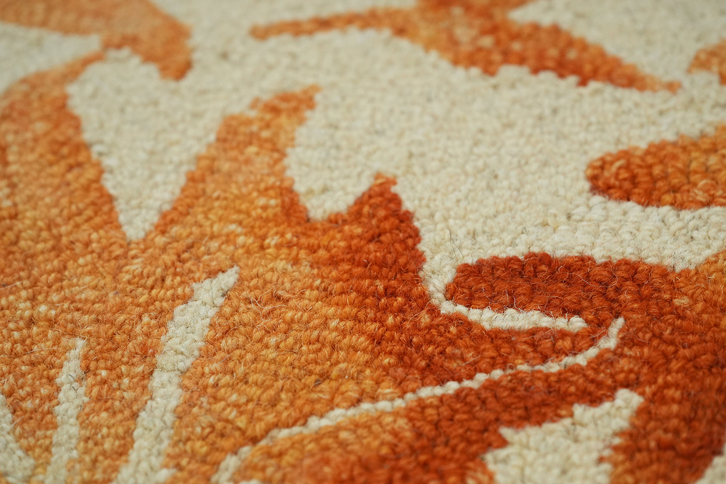 Autumna hand tufted wool rug shown in close up detailing the leaf pattern with layered orange hues and subtle texture