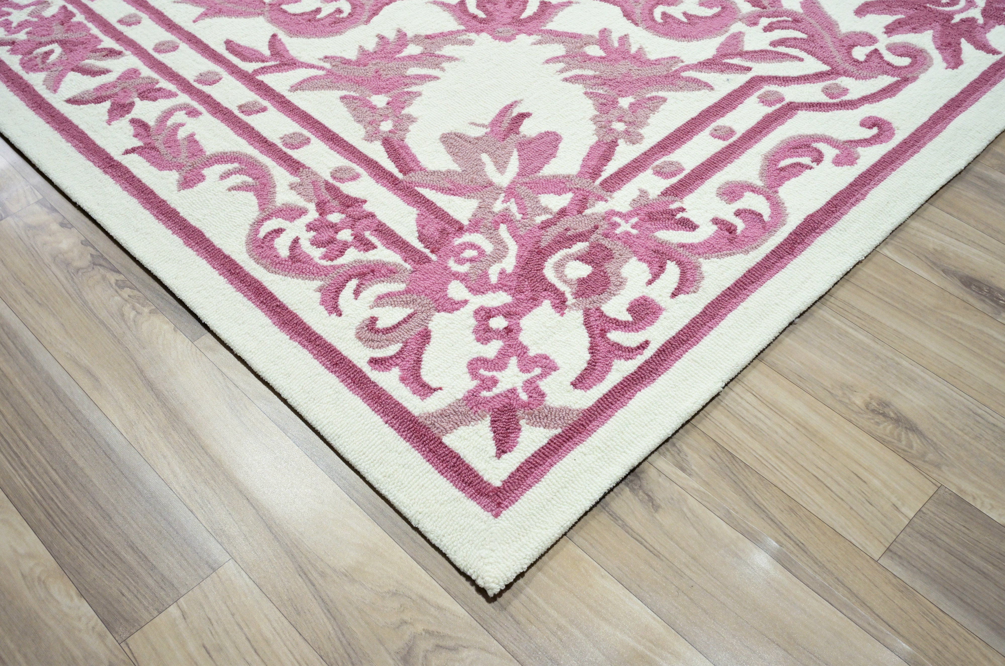 Corner fold of blush ivory hand tufted rug showing thickness and loop pile texture